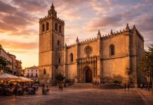 Кафедральный собор Сан-Хуан-Баутиста символ веры и истории Кафедральный собор Сан-Хуан-Баутиста (Catedral de San Juan Bautista) — главный религиозный храм Бадахоса и один из ключевых архитектурных ориентиров исторического центра. Его строгий, почти крепостной облик сразу напоминает о приграничном характере города, который веками находился на линии военных и политических конфликтов между Кастилией и Португалией. Строительство собора началось в XIII веке после христианского завоевания города и продолжалось в течение нескольких столетий. Именно поэтому в его архитектуре сочетаются элементы готики, ренессанса и более поздних стилей. Массивные стены, минималистичный фасад и высокая квадратная башня придают зданию суровую монументальность. Это не декоративный храм южной Испании, а сооружение, в котором чувствуется оборонительная логика эпохи. Главный портал украшен готическими элементами и резьбой по камню, а над входом располагается розеточное окно. Внутри пространство более утончённое: своды, капеллы и алтарные композиции отражают развитие испанского религиозного искусства от позднего Средневековья до барокко. Особое внимание привлекает главный алтарь и орган, подчеркивающие значение собора как духовного центра региона. Собор расположен на площади Испании (Plaza de España), которая исторически служила местом общественной жизни. Здесь проходили религиозные процессии, городские собрания и праздники. Сегодня площадь остаётся живым пространством — с кафе, прогулками и вечерним освещением, которое подчёркивает тёплый цвет камня. Сан-Хуан-Баутиста — это не только религиозный памятник, но и отражение истории Бадахоса: города-крепости, города-границы и города, сумевшего сохранить свою идентичность.