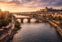 Река Гвадиана в Бадахосе набережные, мосты и городская жизнь у воды Река Гвадиана — главный природный ориентир Бадахоса и одна из тех деталей, без которых невозможно понять характер города. Она не просто делит территорию, а формирует пространство для жизни, прогулок и встреч. Именно вдоль воды выстраивается спокойный, немного созерцательный ритм приграничной столицы Эстремадуры. Набережные Бадахоса — это сочетание исторической атмосферы и современной городской среды. Широкие пешеходные зоны, велодорожки, зелёные аллеи и смотровые площадки создают ощущение открытого пространства. Здесь гуляют семьи, бегают спортсмены, пожилые жители обсуждают новости, а вечером пары встречают закат. Свет Атлантики, смягчённый внутренним климатом региона, делает воду особенно выразительной в золотые часы. Мосты через Гвадиану — важные архитектурные акценты города. Старый мост с каменными арками напоминает о средневековой истории и стратегическом значении Бадахоса как приграничного пункта. Современные переправы, напротив, подчёркивают развитие инфраструктуры и связь с Португалией. Они не спорят с прошлым, а аккуратно вписываются в панораму. С воды открывается один из самых выразительных видов на город: силуэт крепостных стен Алькасабы, башни, купола и белые фасады домов. Гвадиана отражает их, создавая двойной пейзаж — реальный и зеркальный. В тёплое время года здесь проходят небольшие городские мероприятия, спортивные активности и локальные фестивали. Важно и экологическое значение реки. Вдоль берегов обустроены зелёные зоны, где можно увидеть птиц и характерную для региона растительность. Это делает пространство не только урбанистическим, но и природным. Гвадиана в Бадахосе — это граница и связующее звено одновременно. Она напоминает о стратегической роли города в истории, но при этом создаёт спокойную, открытую атмосферу современной жизни у воды.