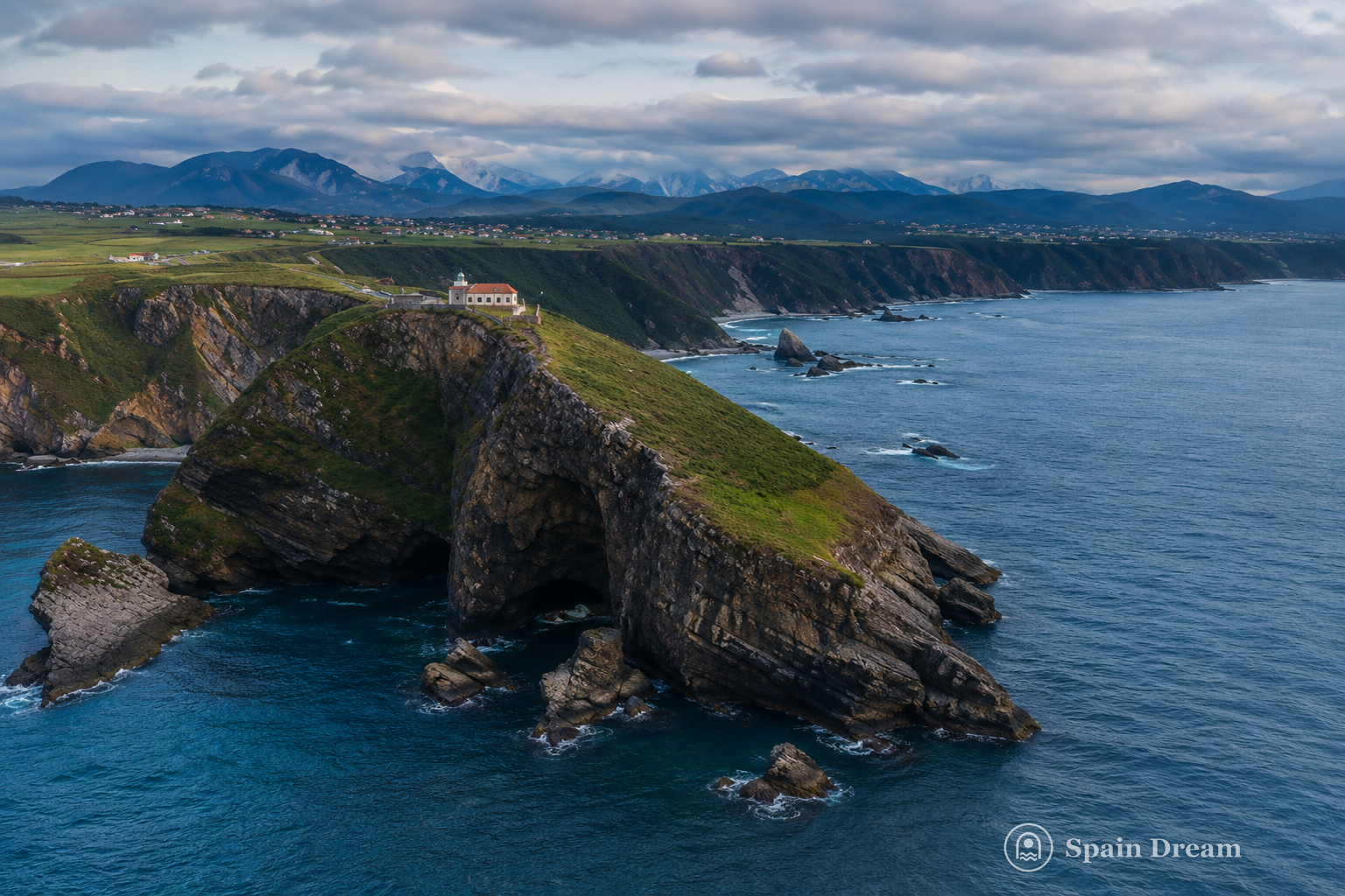 Playa del Silencio у Кудильеро с галечным берегом, высокими зелёными скалами и каменными островками в Кантабрийском море